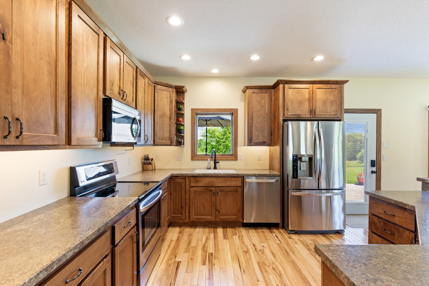 Galley view of the kitchen with corner sink and window