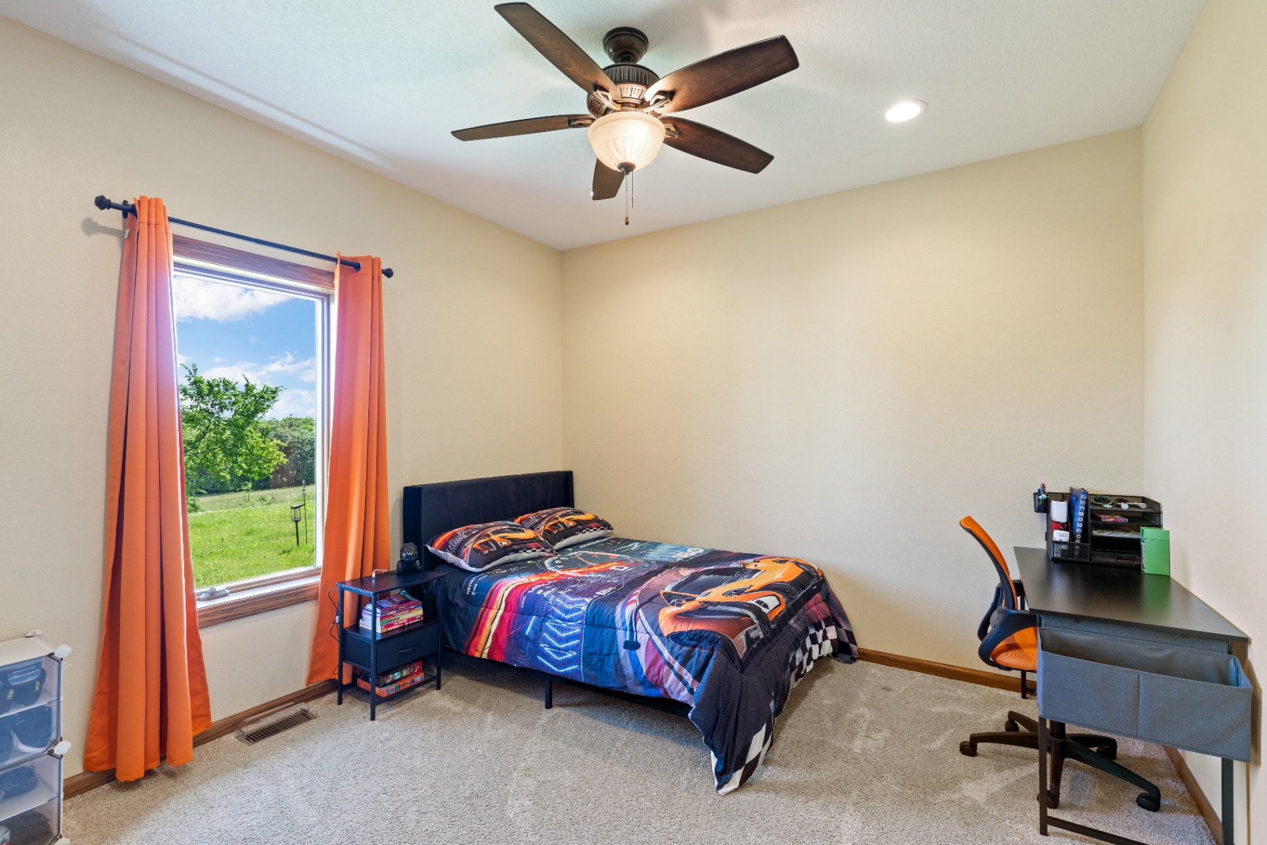 Bedroom with orange curtains, desk, and racing-themed bedding