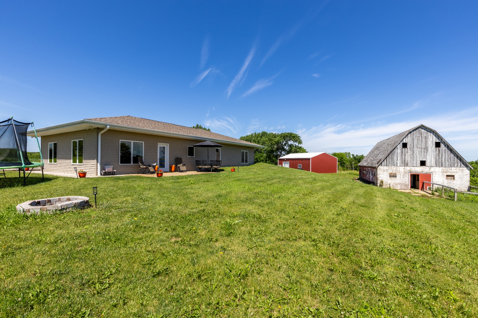 Wide backyard view with ranch home, barn, and outbuilding