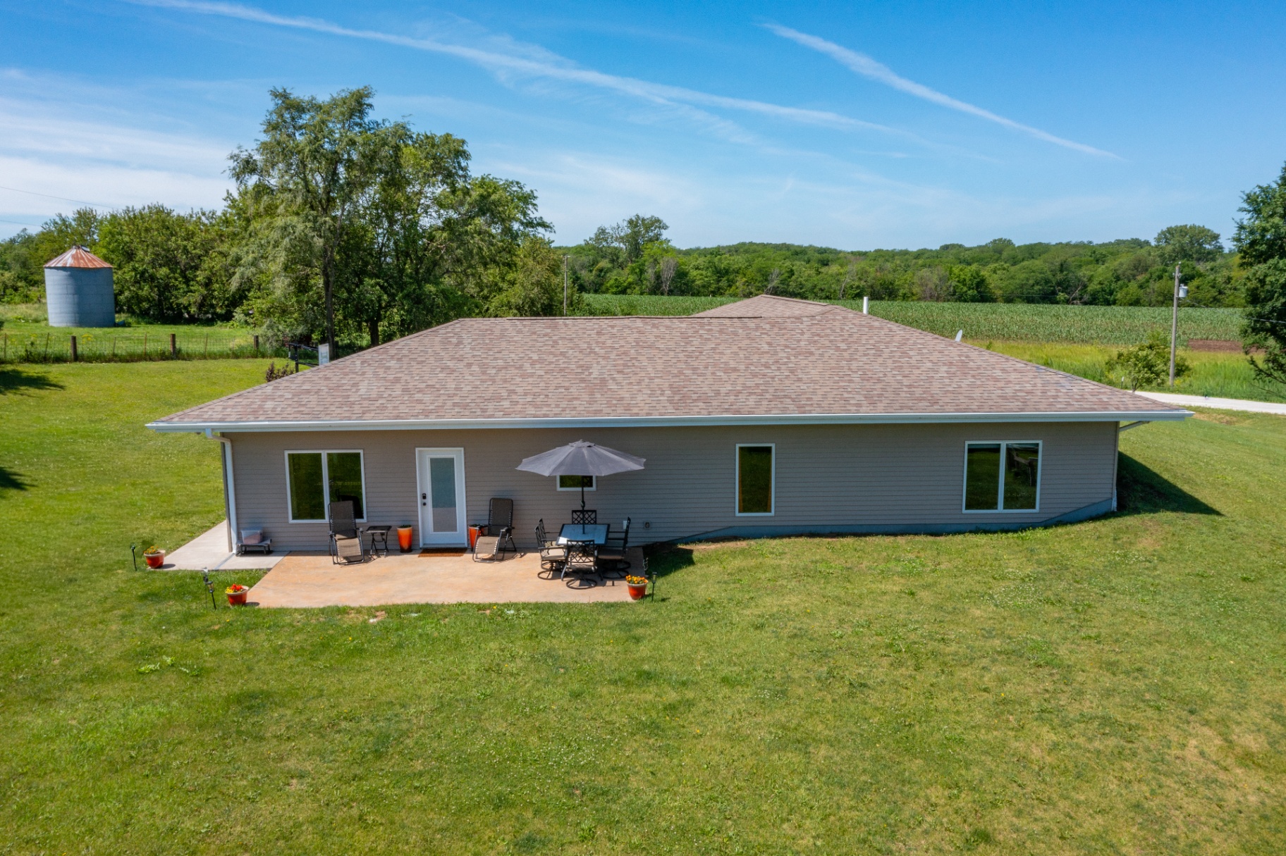 Rear elevation of the ranch with patio seating and grain bin